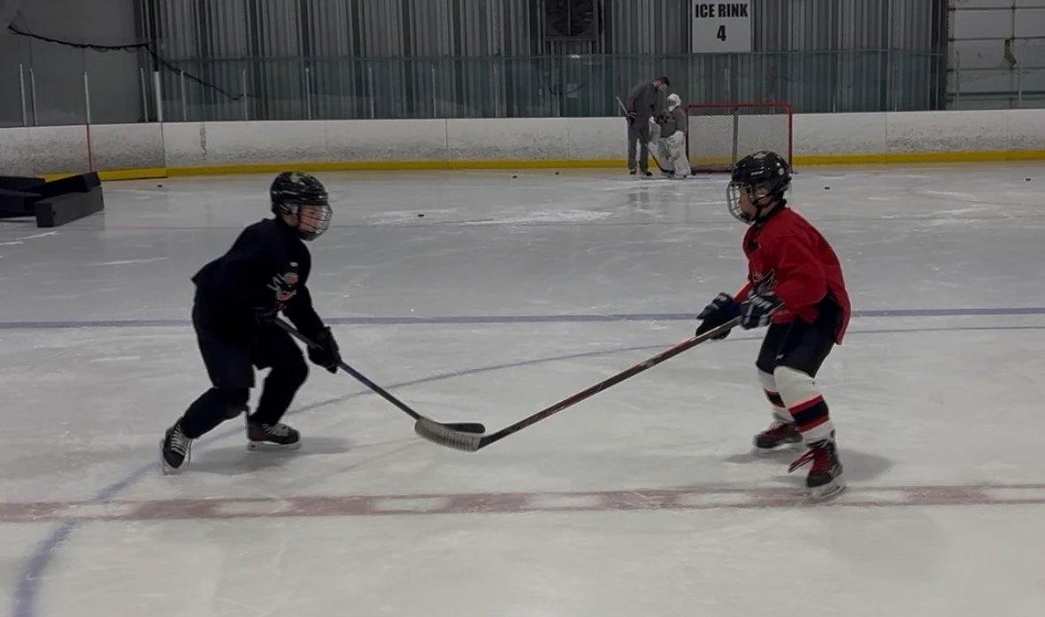 Two Falcons players battle one-on-one during a position-specific session as a goalie works in the net behind them